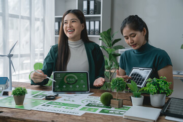 Two happy female environmental engineers discussing an esg project with solar panel and wind...