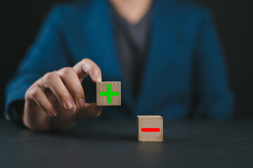 Wooden block show plus and minus symbols. The concept of opposites, decisions, and uncertainty....
