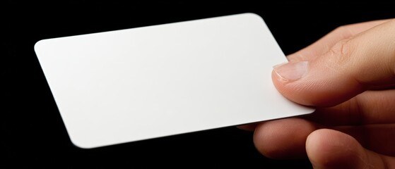 Obraz premium Person Holding Empty White Business Card Against Black Background for Professional Networking and Marketing
