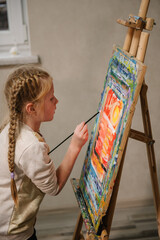Child draw a picture in art class. Girl enjoys painting in a workshop. Art lesson. Education and...