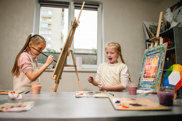 Group of school children drawing with brush landscapes on easel. Childs enjoy painting in workshop....