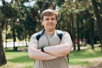 Happy 30s blonde man with backpack standing in the countryside. Traveler. Summer time. Portrait of...
