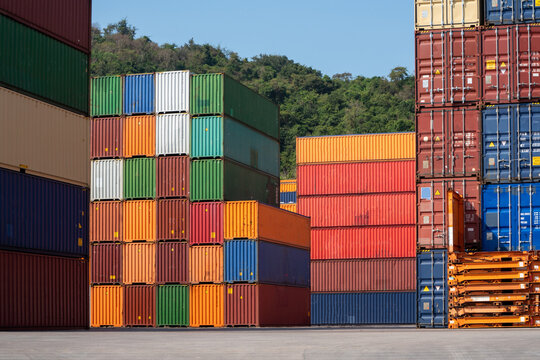 Colorful stacked shipping containers in a freight yard under clear sky, representing global logistics, cargo transport, and supply chain management. - Powered by Adobe