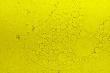 Macro abstract image of golden oil bubbles suspended in liquid, forming overlapping circular...
