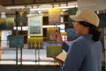 Woman observing artwork in modern art gallery. Captures moment of thoughtful appreciation, ideal for themes of creativity, inspiration, education, and cultural exploration.