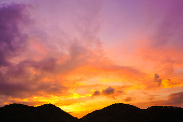 sunset sky with dramatic purple, pink, and orange clouds over silhouette mountains. Captures peaceful nature and magical twilight moment for background, travel, and nature concepts.