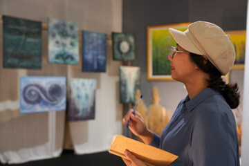Woman observing artwork in modern art gallery. Captures moment of thoughtful appreciation, ideal for themes of creativity, inspiration, education, and cultural exploration.
