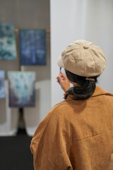 Woman observing artwork in modern art gallery. Captures moment of thoughtful appreciation, ideal for themes of creativity, inspiration, education, and cultural exploration.