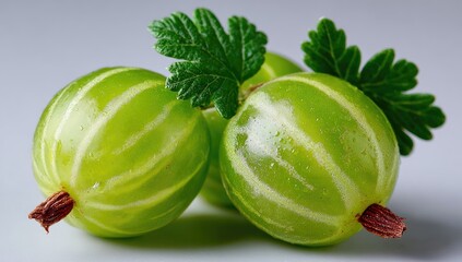 Close-up of three bright green gooseberries with leaves