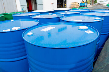 Blue industrial steel drums arranged outdoors near a warehouse, used for storing chemicals, oils,...