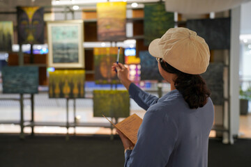 Woman observing artwork in modern art gallery. Captures moment of thoughtful appreciation, ideal for themes of creativity, inspiration, education, and cultural exploration.