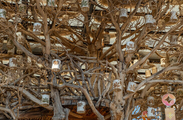 a rustic, ceiling installation featuring a large, leafless tree with intricate, twisting branches....