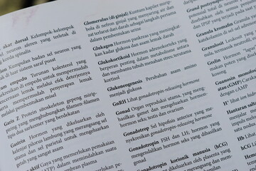 Fototapeta premium A close-up of an open medical textbook, showing detailed text and diagrams about human physiology and biology. This image represents study, education, research, and the journey of a medical student.