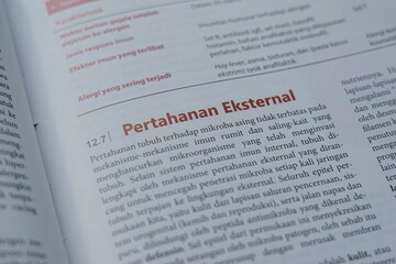 A close-up of an open medical textbook, showing detailed text and diagrams about human physiology and biology. This image represents study, education, research, and the journey of a medical student.