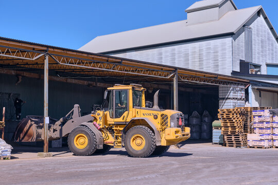 Bj&auml;rne Kvarn cooperative feed mill on Swedish countryside with Volvo wheel loader loading grain under canopy of corrugated metal