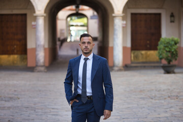 Young, brunette, Hispanic, modern executive, in suit and tie, walking down a lonely city street...