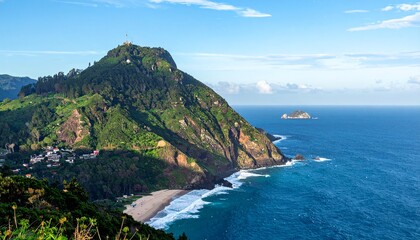Scenic coastal landscape featuring a lush green mountain, ocean, and a distant island under a clear blue sky.