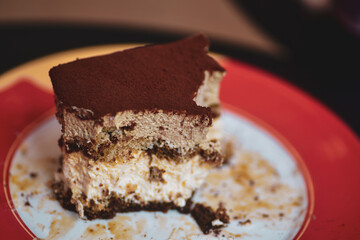 Tiramisu Dessert: A delicious slice of tiramisu, a layered Italian dessert, artfully presented on a red plate. The photo emphasizes the delightful texture and flavor.