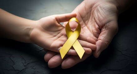 Adult and child hands holding gold ribbon together, banner template for childhood cancer awareness month family care health support and charity campaign with copyspace.