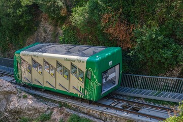 Green Sant Joan Funicular Railway Car Traveling Through Montserrat Mountain. Mountain railway...