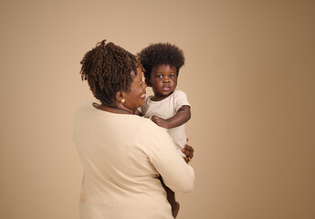 Mother embraces her toddler over her shoulder, capturing themes of comfort, security, and family...