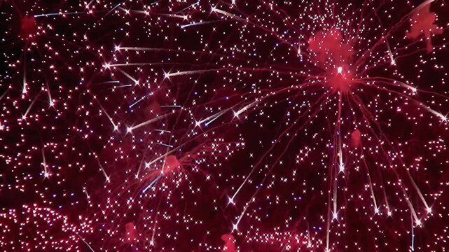 Witness ruby red Fireworks lighting up the night sky in a mesmerizing display. Sparkling trails and radiant bursts create a captivating light show during the celebration.