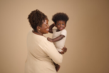A cheerful child embraces their mother, smiling brightly in a minimalist studio portrait of family...