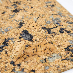 Close-up of a natural cork sheet with textured black and grey inclusions. Eco-friendly material ideal for interiors, crafts, and design projects.