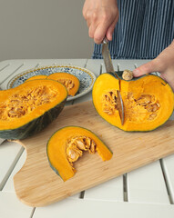 Anonymous cut pumpkin on wooden board. Farm products and healthy eating. Seasonal food, vegetarian...