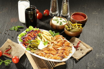 Traditional Turkish Doner Kebab Plate with Fresh Vegetables, French Fries, and Sauces on Rustic Background
