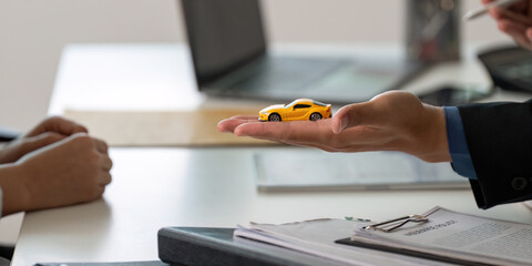 Insurance Consultation. Agent presenting a toy car while discussing coverage options.