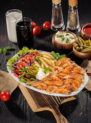 Traditional Turkish Doner Kebab Plate with Fresh Vegetables, French Fries, and Sauces on Rustic Background
