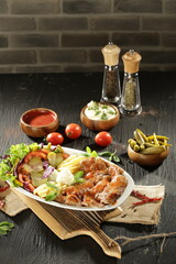 Traditional Turkish Doner Kebab Plate with Fresh Vegetables, French Fries, and Sauces on Rustic Background