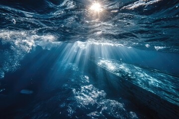 Sunbeams pierce dark ocean depths, illuminating underwater scene