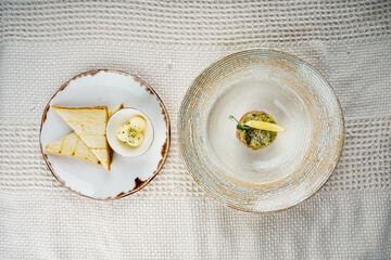 Salmon tartare with avocado and bread with spread on a white background