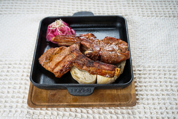 Grilled pork chops in a frying pan on a white background