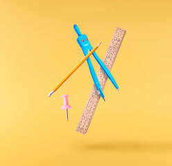 Back to school conception. Flying in the air school equipment isolated on yellow background