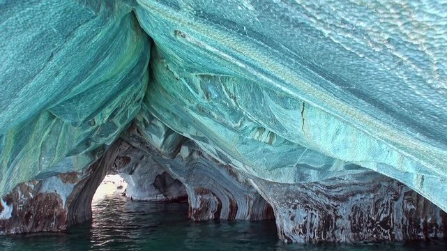 Journey into the Marble Caves of Patagonia, Argentina. Turquoise water flows through these magnificent geological wonders carved over millennia. Light dances across the cavern walls.