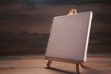 Easel with blank canvas on wooden background. Mockup for design
