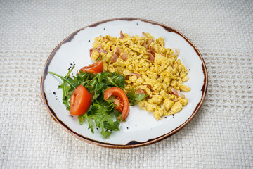 Scramble with baby lettuce and tomatoes on a plate on the background