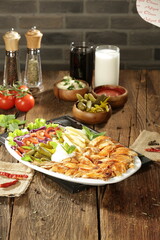 "Traditional Turkish Doner Kebab Plate with Fresh Vegetables, French Fries, and Sauces on Rustic Background"