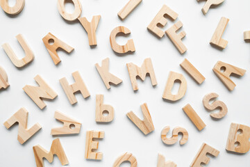 Scattered wooden letters on white background displaying the alphabet