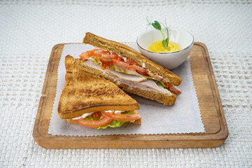 Ham and tomato sandwich on a wooden board on a white background