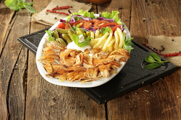 "Traditional Turkish Doner Kebab Plate with Fresh Vegetables, French Fries, and Sauces on Rustic Background"