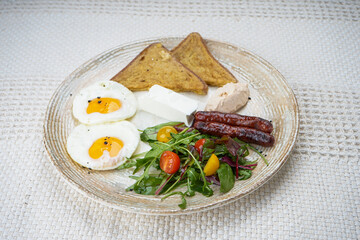breakfast with egg, sausages and salad on a plate on the background