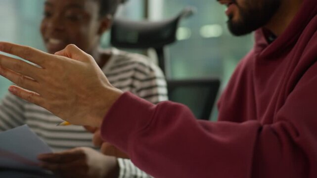 Informal business team collaboration Arabian man examining papers African woman holding chart comunicate Indian male colleague pointing at laptop casual diversity teamwork modern office briefing job