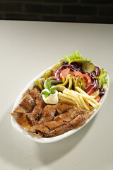 Traditional Turkish Chicken Doner Kebab Plate with French Fries, Pickles and Fresh Vegetables on white background
