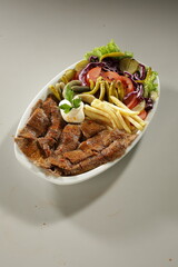 Traditional Turkish Chicken Doner Kebab Plate with French Fries, Pickles and Fresh Vegetables on white background
