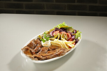 Traditional Turkish Chicken Doner Kebab Plate with French Fries, Pickles and Fresh Vegetables on white background
