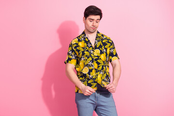 Young man wearing a tropical print shirt posing playfully against a vibrant pink background...